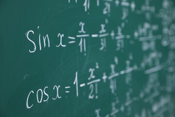 Different formulas written with chalk on blackboard, closeup