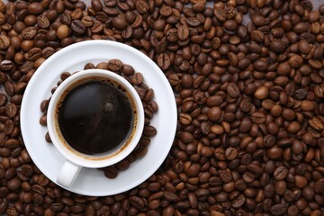 Aromatic coffee in cup, saucer and beans, top view