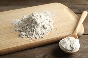Pile of flour and spoon on wooden table, closeup