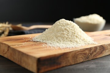 Pile of flour on dark wooden table against black background, closeup
