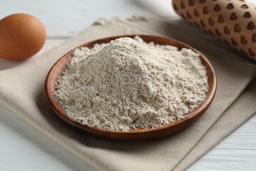 Flour, rolling pin and egg on white wooden table, closeup