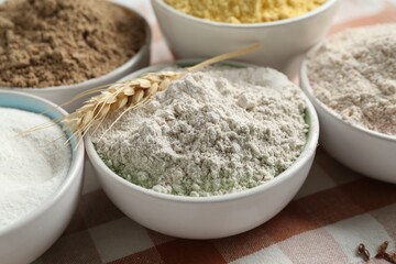 Different types of flour in bowls on table, closeup