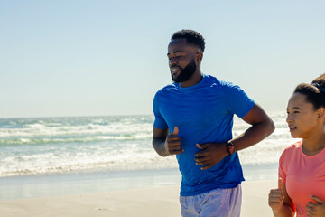 Fototapeta premium Couple jogging on beach, enjoying sunny day and staying fit together