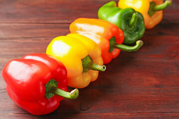 Ripe colorful bell peppers on wooden table, closeup