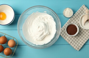 Bowl with whipped cream and ingredients on light blue wooden table, flat lay