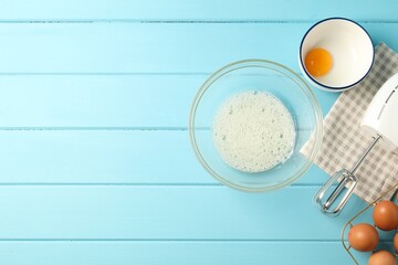 Making whipped cream. Bowl, hand mixer and ingredients on light blue wooden table, flat lay. Space for text