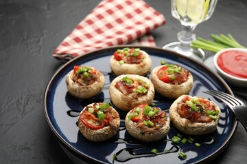 Tasty stuffed mushrooms served on black table, closeup