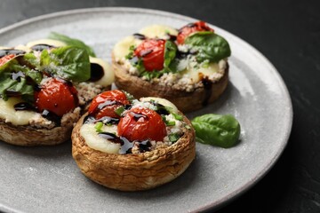 Tasty stuffed mushrooms served on black table, closeup