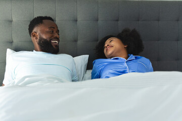 Couple relaxing in bed, smiling and enjoying morning conversation together