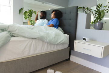 Couple relaxing in bed, smiling and enjoying morning sunlight at home
