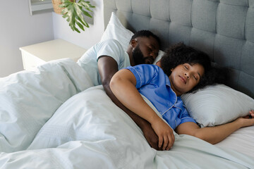 African American couple peacefully sleeping in bed, embracing each other lovingly