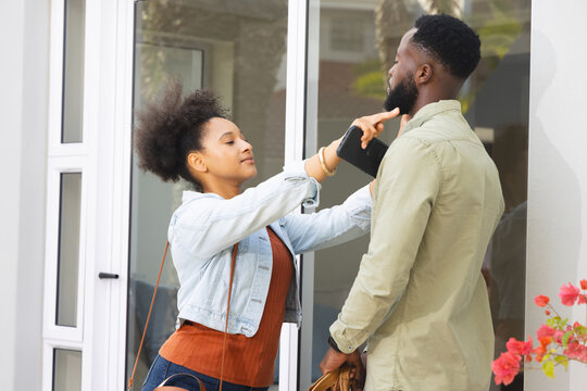 Young couple playfully interacting outside modern home, enjoying lighthearted moment