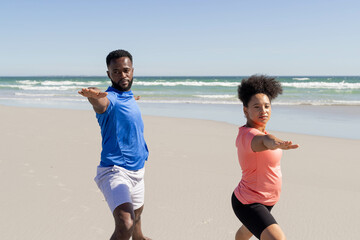 Fototapeta premium Couple practicing yoga on beach, focusing on balance and relaxation together
