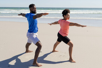 Fototapeta premium Couple practicing yoga on beach, enjoying sunny day and ocean view