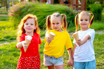 happy children eating ice cream in the summer on the green lawn in the park, a bright summer photo of children's holidays, three baby girls laughing and having fun in the summer