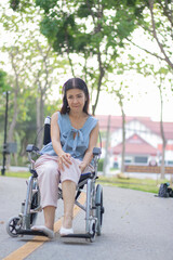 Obraz premium A smiling elderly woman in a wheelchair sits outdoors with her caregiver, sharing a hopeful conversation during a rehabilitation treatment for arthritis in her leg.