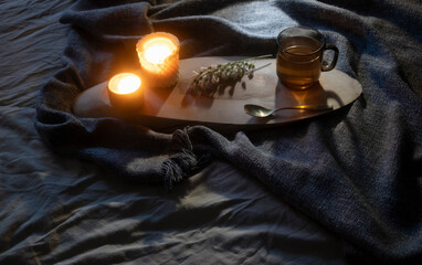 cup of tea with burning candles on bed