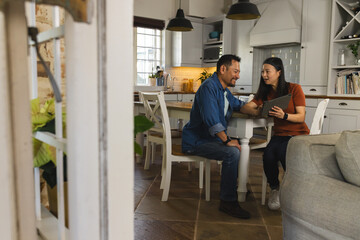 Mature Asian couple in kitchen discussing plans while using digital tablet together