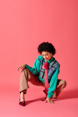 Fototapeta premium Young beautiful woman showcasing vibrant fashion style against a lively pink backdrop