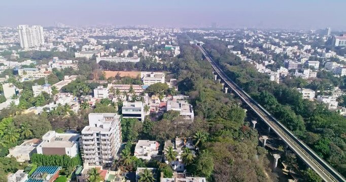 Aerial tracking shot of namma metro green line railroad track amidst lush city in bangalore,india