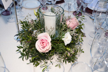 Elegant wedding reception setup with round tables, floral centerpieces and champagne glasses in a beautifully decorated venue.