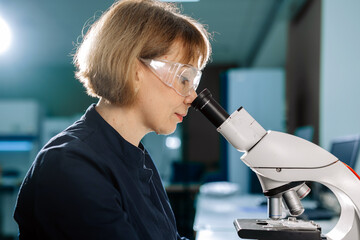 A scientist works with a microscope in the laboratory. Conducts research of biomaterial samples.