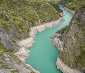Obraz premium Scenic view of Lake Monteynard-Avignonet in a canyon in the French Alps near Grenoble, turquoise mountain lake surrounded by alpine peaks and forests