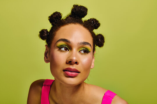 Young beautiful woman showcases vibrant fashion and bold makeup against a vivid green backdrop