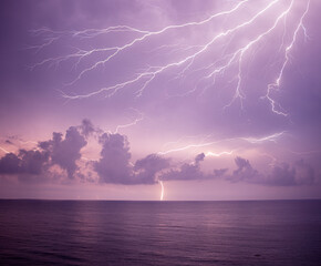 Dramatic lightning strike over the sea during thunderstorm at night.