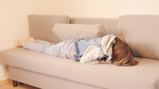 12-year-old boy in frustration, lying on sofa, punching pillows, experiencing teenage angst and tantrums, coping with emotions, angst and frustration, mental health