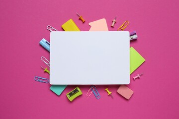 A collection of school supplies arranged around a white card on a coloured background, ideal for...