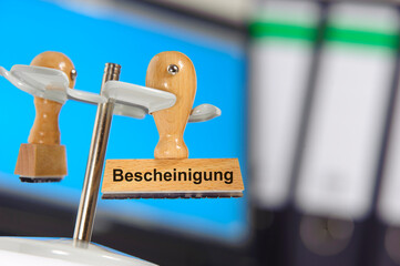 Ein Holzstempel ist beschriftet mit dem Aufdruck Bescheinigung