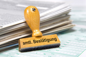 Ein Holzstempel ist beschriftet mit dem Aufdruck amtliche Bestätigung