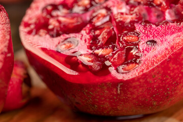 sliced red ripe pomegranate on a table, sweet red pomegranate cut into pieces during cooking