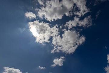 sky with clouds in sunny bright weather, natural blue sky with cumulus clouds illuminated by sunlight