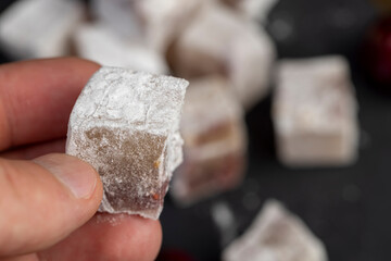 Turkish delight with cherry on a black slate , cubes of sweet Turkish delight with red berries , sweets in hands