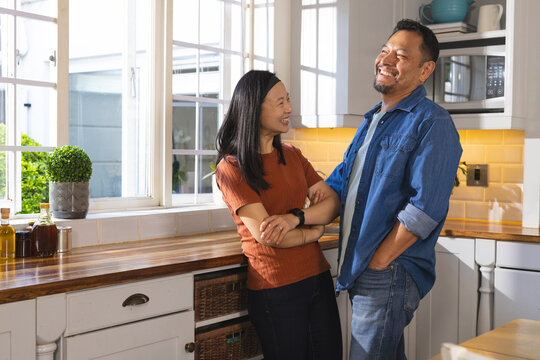 Mature couple laughing together in bright kitchen, enjoying quality time at home