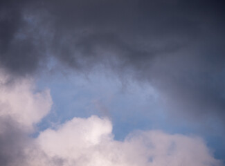 Dark and light clouds in the sky with soft blue showing through. A moody and natural weather scene, capturing a moment before or after rain.