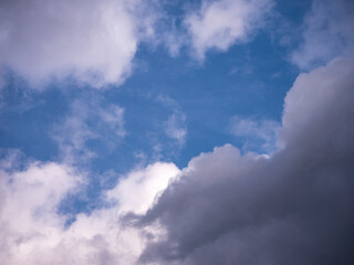 Blue sky with a mix of white and dark clouds, showing a transition in weather. A natural and atmospheric scene with a calm yet slightly dramatic mood.