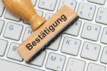Ein Holzstempel ist beschriftet mit dem Aufdruck Bestätigung