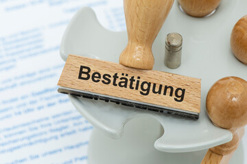 Ein Holzstempel ist beschriftet mit dem Aufdruck Bestätigung