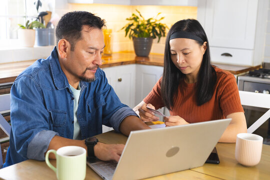 Mature couple at home using laptop and credit card for online shopping