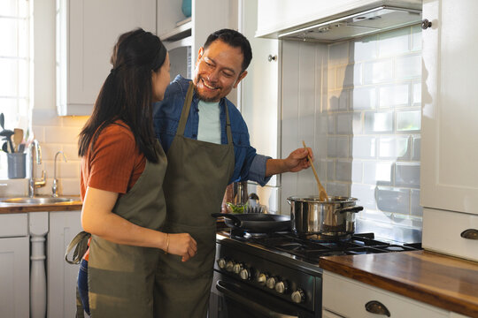 Mature couple cooking together in kitchen, smiling and enjoying quality time