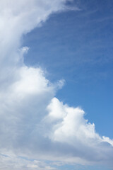 Bright blue sky with dramatic, fluffy white clouds forming a scenic and peaceful atmosphere. Ideal for nature backgrounds, weather concepts, or tranquil skyscape visuals.