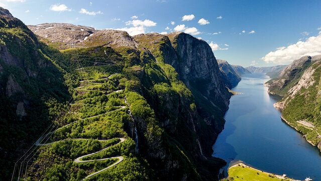 Breathtaking aerial view of lush green hills and serene fjord in Norway under a clear blue sky