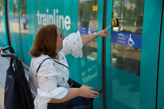 Woman in wheelchair using accessible public transport button - wheelchair and disability concept