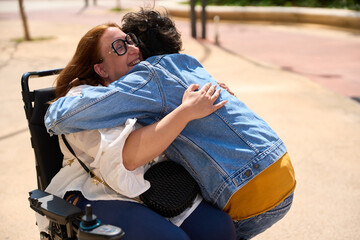 Heartfelt hug between friends in wheelchair - wheelchair and disability concept
