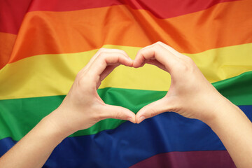 Hands showing heart and love against LGBT flag.