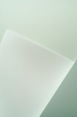 Flat lay of light green and white paper with subtle gradient, featuring a soft-edged triangular shape in the corner