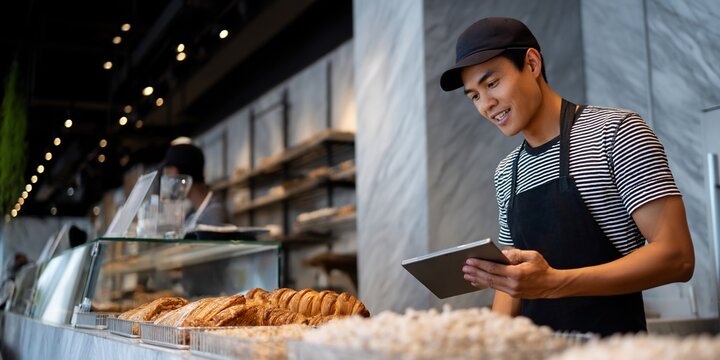 A bakery worker uses a tablet in a modern bakery